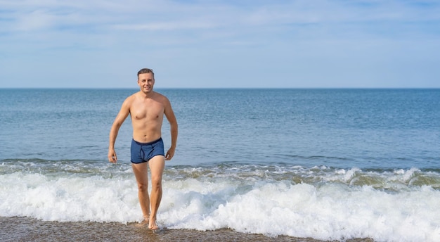 Foto homem alegre saindo do mar