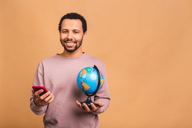 Homem alegre segurando o globo com amor e carinho, isolado sobre o bege