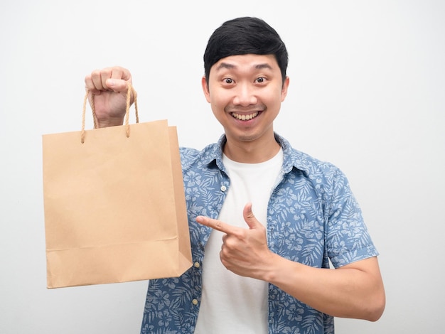 Homem alegre, sorrindo, apontando o dedo para a sacola de compras na mão