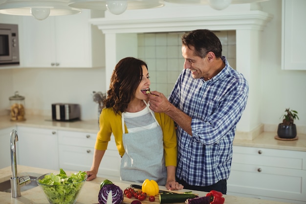 Homem alimentando mulher na cozinha