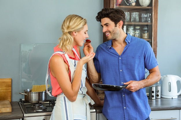 Homem alimentando sua mulher na cozinha