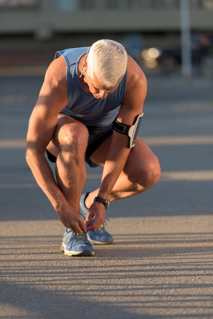 Homem amarrando o cadarço do tênis de corrida antes do treino de jogging