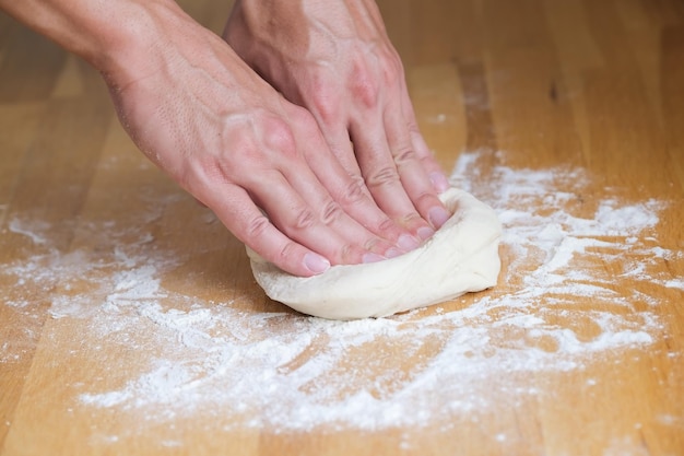 Homem amassar massa e fazer pizza em casa