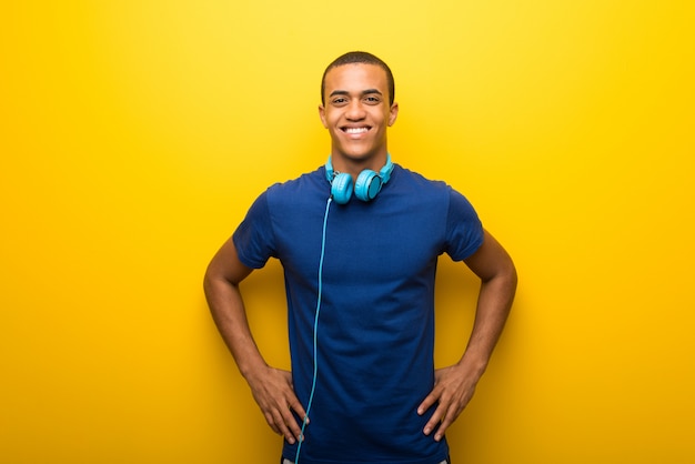 Homem americano africano, com, azul, t-shirt, ligado, experiência amarela, posar, com, braços quadril