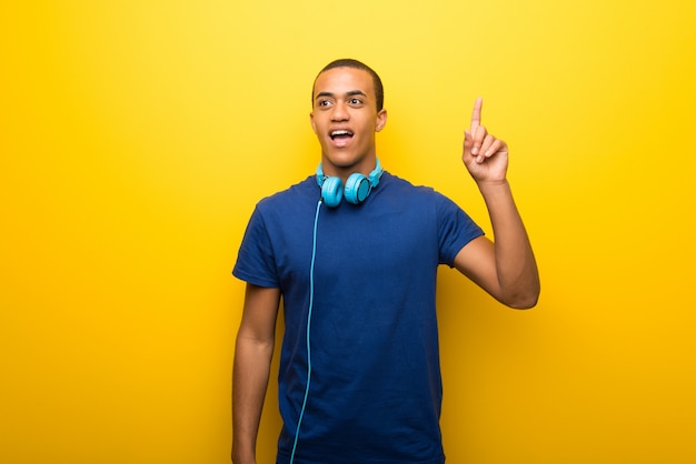 Homem americano africano, com, t-shirt azul, ligado, experiência amarela, pensando, um, idéia, apontar, a, dedo cima