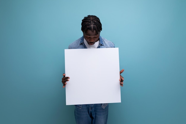 Homem americano com dreadlocks em uma jaqueta jeans demonstra um cartaz de papel com uma maquete