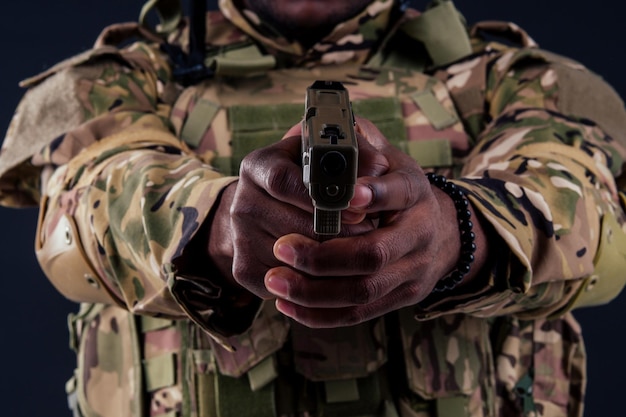 Homem americano em traje de camuflagem apontando com uma pistola