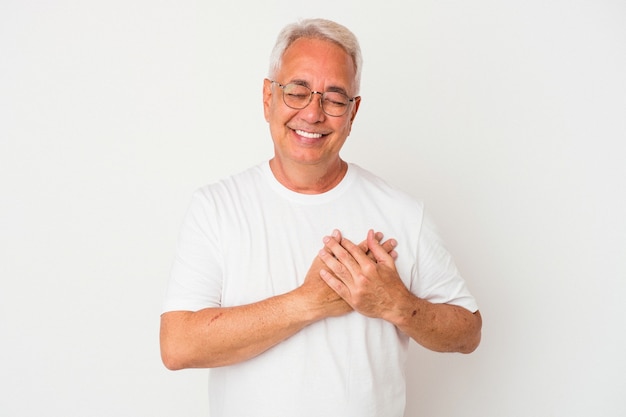 Homem americano sênior isolado no fundo branco rindo mantendo as mãos no coração, o conceito de felicidade.