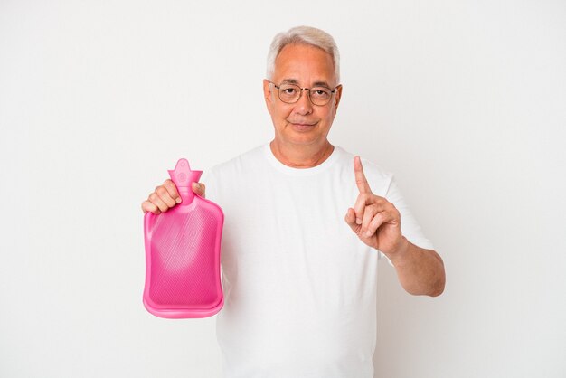 Homem americano sênior segurando uma garrafa de água quente, isolada no fundo branco, mostrando o número um com o dedo.