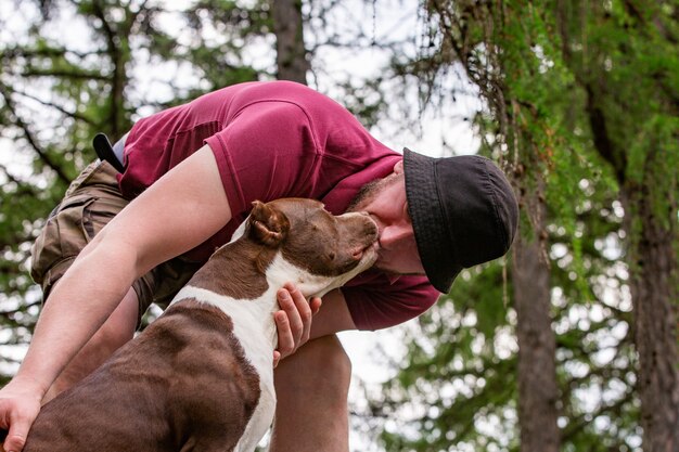 Homem andando com cachorro no parque e beijando