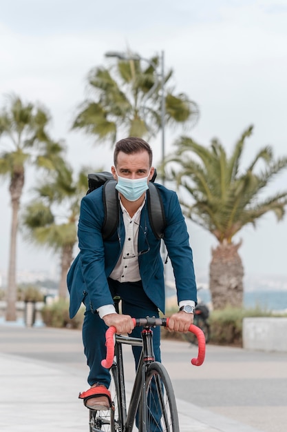 Homem andando de bicicleta com máscara médica para trabalhar