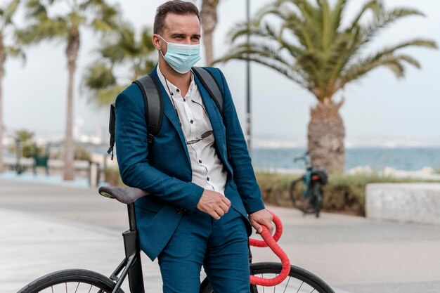 Homem andando de bicicleta com máscara médica para trabalhar