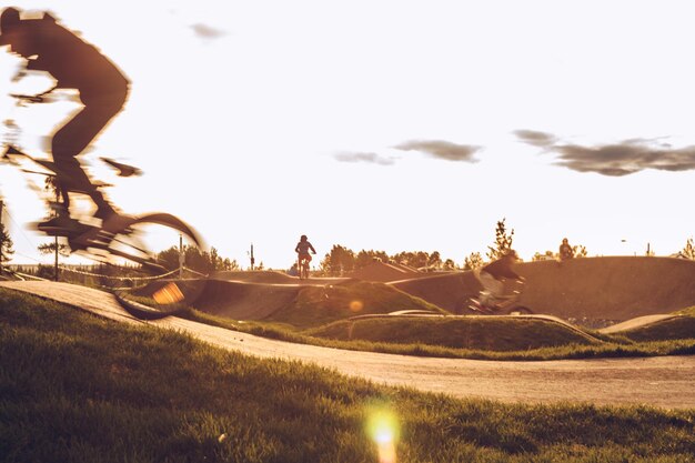 Foto homem andando de bicicleta contra o céu durante o pôr do sol