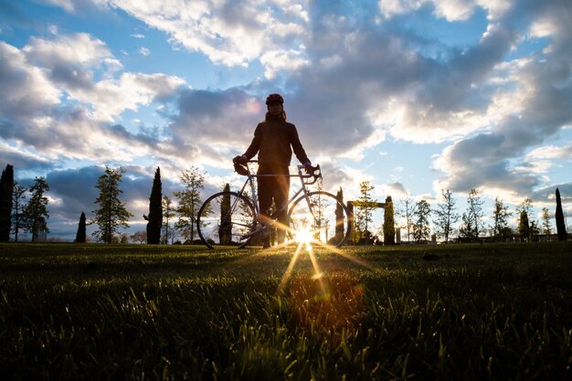 Foto homem andando de bicicleta no campo contra o céu durante o pôr do sol