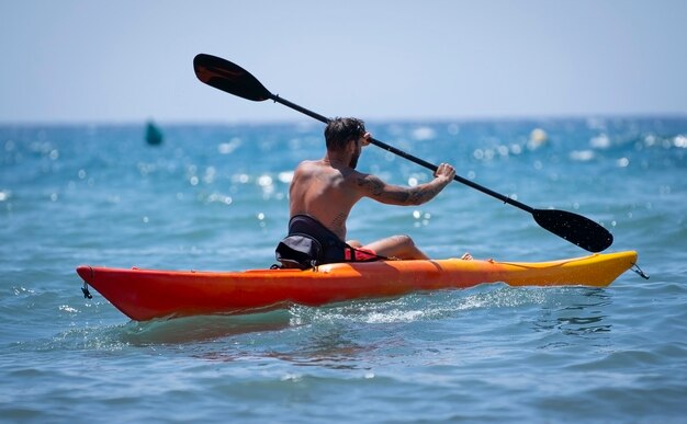 Homem andando de caiaque na praia durante as férias de verão