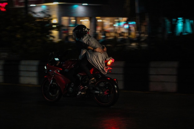 Homem andando de motocicleta na rua iluminada à noite