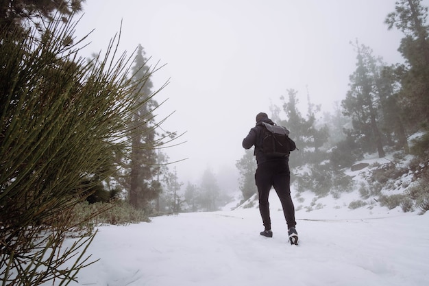 homem andando na neve em paisagem montanhosa