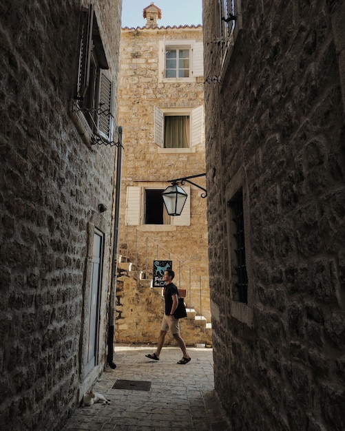 Homem andando na pequena rua com edifícios de pedra na cidade velha budva montenegro