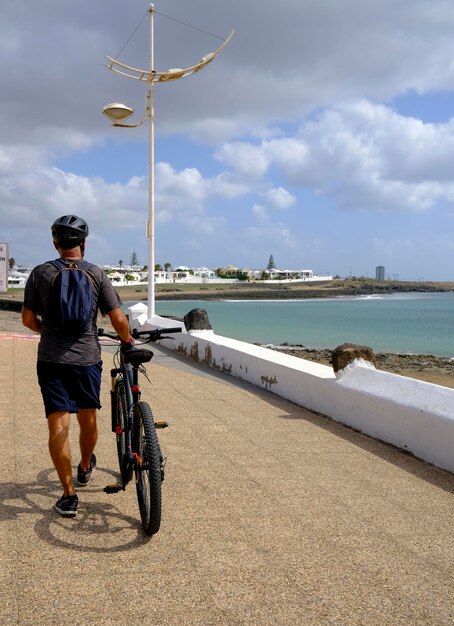 Homem andando no calçadão da praia de bicicleta