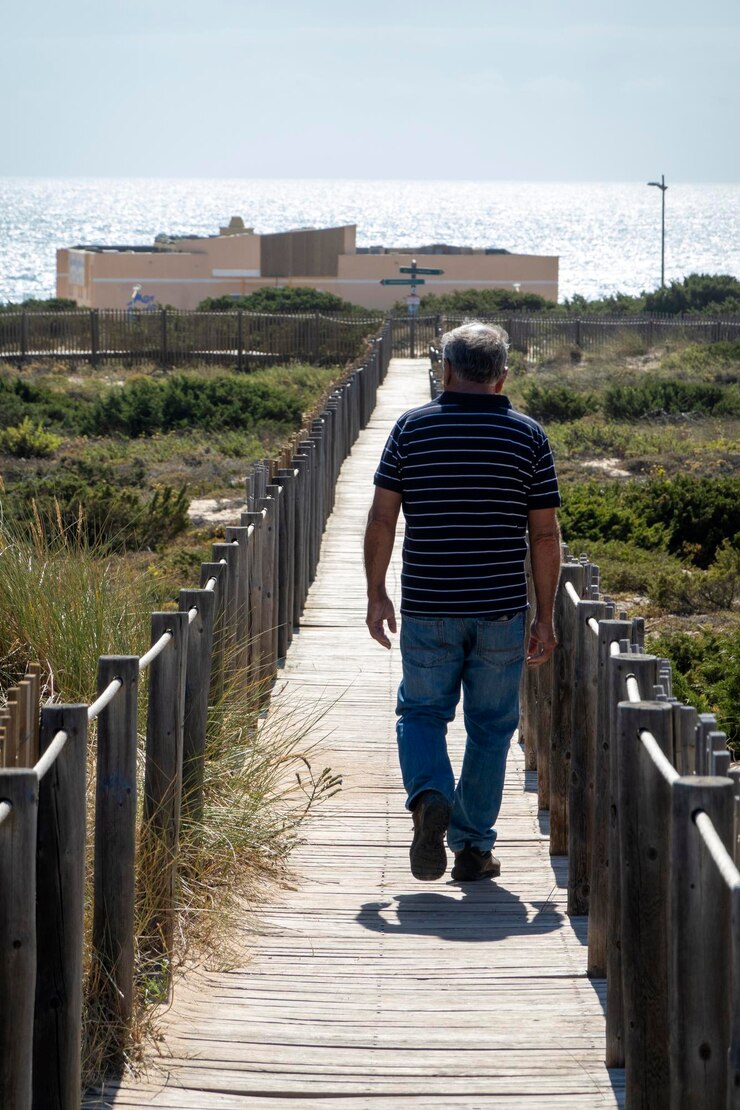 Foto homem andando no caminho de madeira do guincho pelas dunas de areia