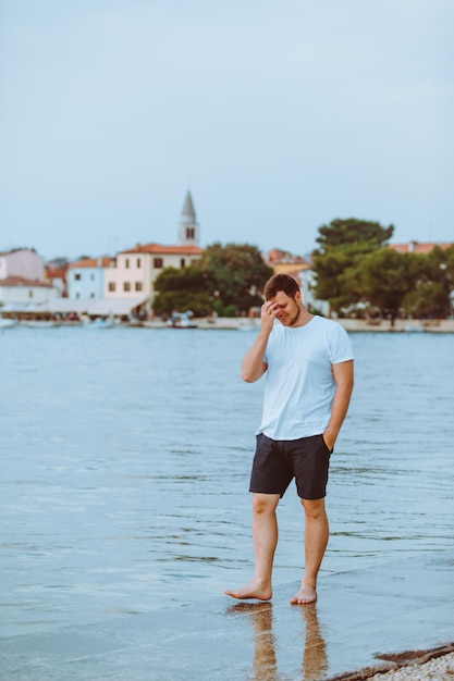 Foto homem andando pela praia do mar na cidade de fazana de noite de verão no fundo na croácia