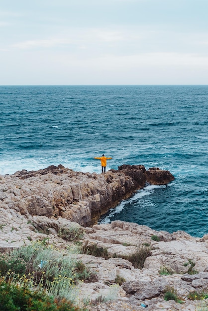 Homem andando pela rocha para o mar tempestuoso