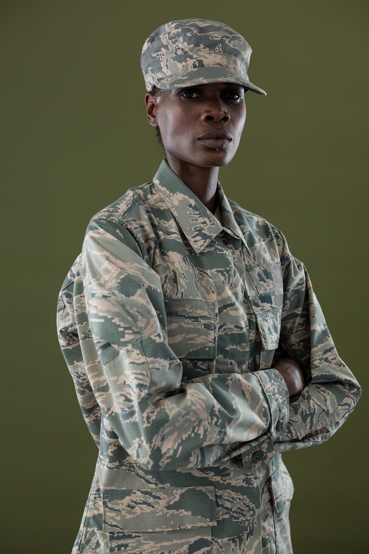 Foto homem andrógino com uniforme camuflado em pé com os braços cruzados