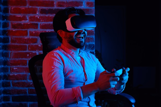 Homem animado sorrindo enquanto joga com óculos de VR, sentado na cadeira