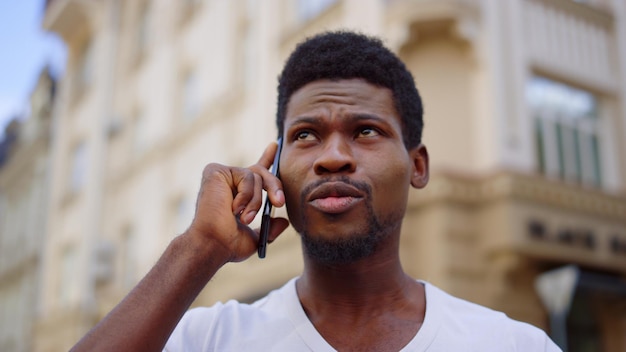 Homem ansioso falando móvel na cidade afro cara conversando por telefone na rua