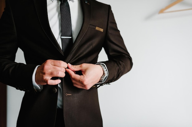 Homem aperta os botões O noivo em uma gravata de terno está de pé sobre fundo branco Fechar