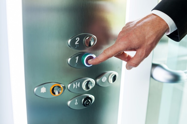 Homem apertando o botão. Close de uma mão masculina apertando o botão do elevador