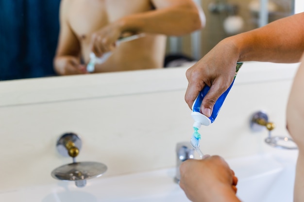 Homem, apertando, pasta de dentes, em, escova de dentes, em, a, banheiro