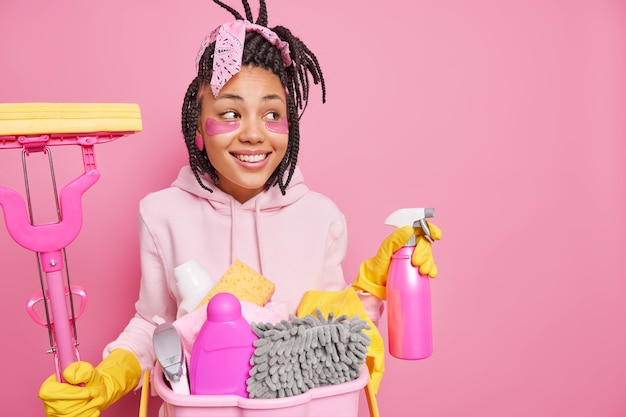 homem aplica patches de beleza segura o esfregão e detergente de limpeza limpa a sala usa detergentes químicos parece de lado poses em rosa