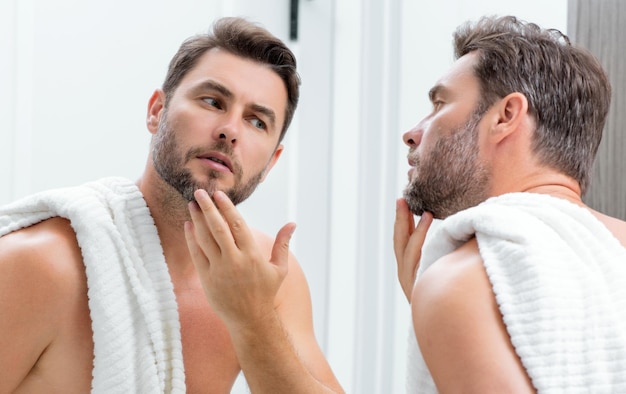 Homem aplicando creme facial cosmético em tratamento facial de espelho retrato de homem com nu desnudo