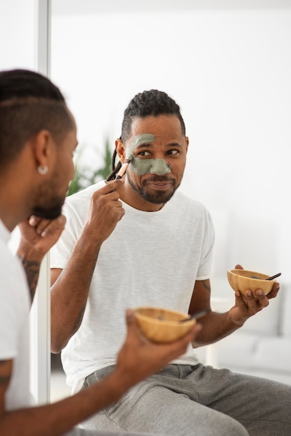 Homem aplicando tratamento facial com pincel close up