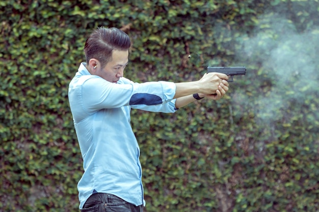 Foto homem apontando com uma pistola enquanto está de pé ao ar livre