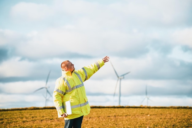 Homem apontando para o céu em pé perto de turbinas eólicas Futuro sustentável e conceito de fontes de energia renováveis