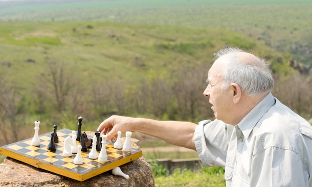 Homem aposentado jogando xadrez no campo