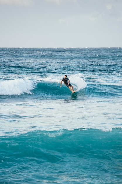 Foto homem aproveitando o tempo na prancha de surf entre as ondas