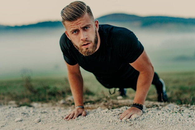 Homem apto fazendo exercícios de flexões no ginásio ao ar livre. Atleta de treino de corpo central fazendo prancha ou fazendo flexão na grama.