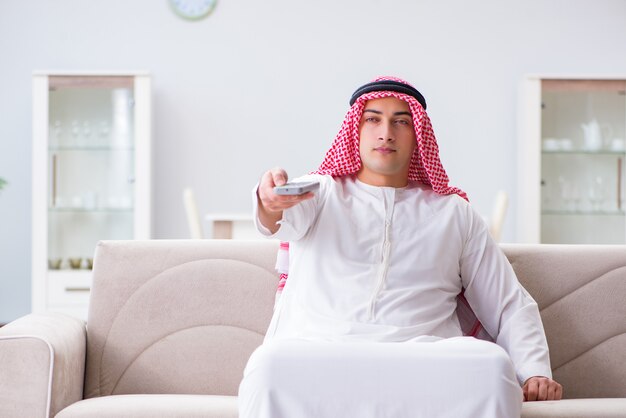 Homem árabe assistindo tv em casa