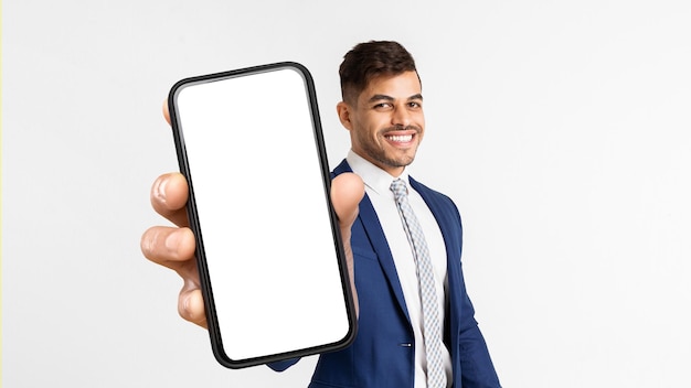 Foto homem árabe feliz sorrindo e mostrando maquete de telefone celular