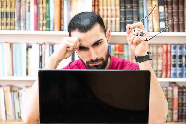 Homem árabe usando um laptop durante conferências ou reuniões para estudar e ensinar por meio de canais online