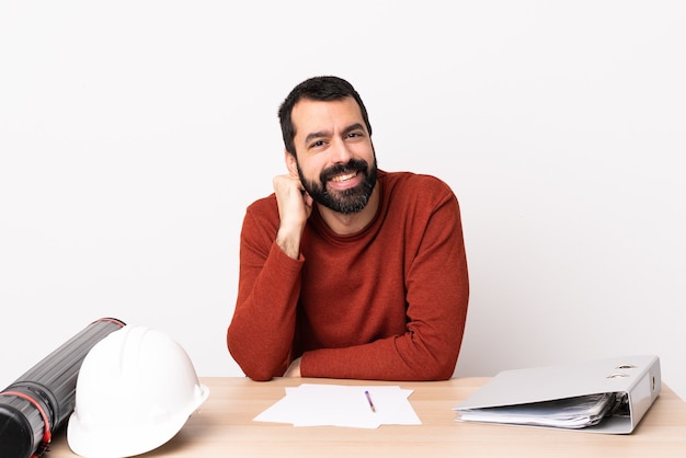 Homem arquiteto caucasiano com barba em uma mesa rindo.