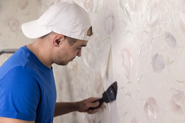 Foto homem arrancando papel de parede antigo com raspador de parede closeup reparos cosméticos no apartamento copiar espaço