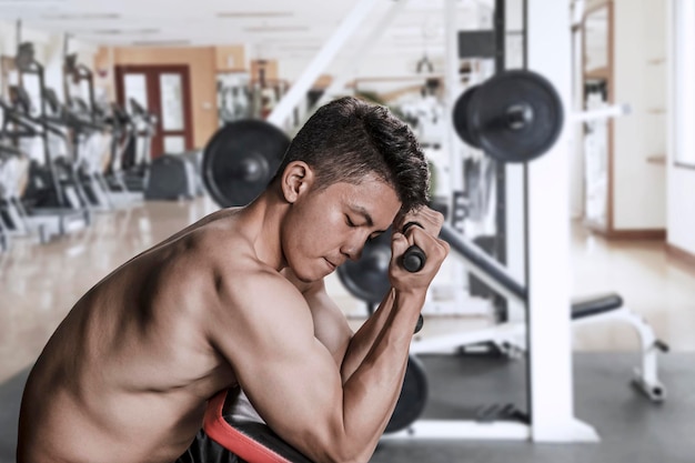 Foto homem asiático a fazer exercício com uma máquina de pesos