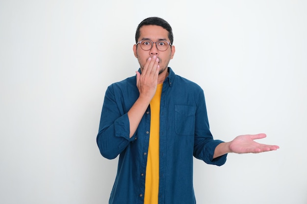Homem asiático adulto cobre a boca com uma mão e mostra expressão chocada