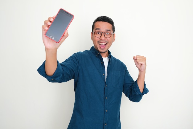 Homem asiático adulto mostrando a tela do telefone em branco com expressão animada