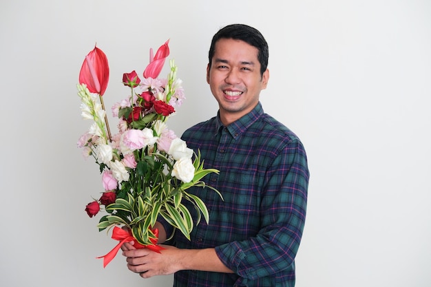 Homem asiático adulto sorrindo feliz ao segurar o arranjo de flores