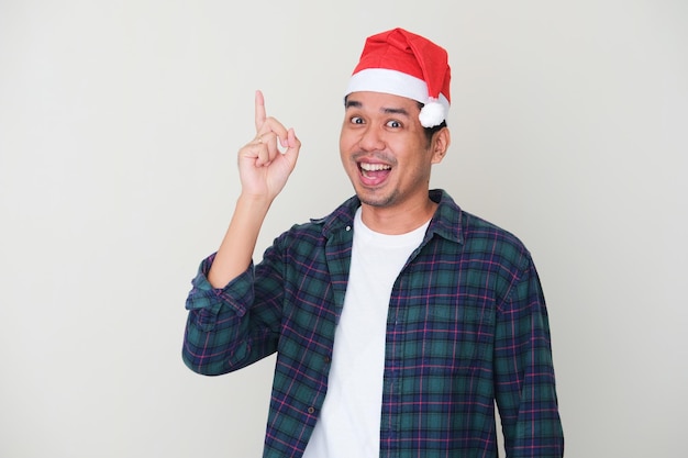 Homem asiático adulto usando chapéu de Natal para fazer um gesto de boa ideia